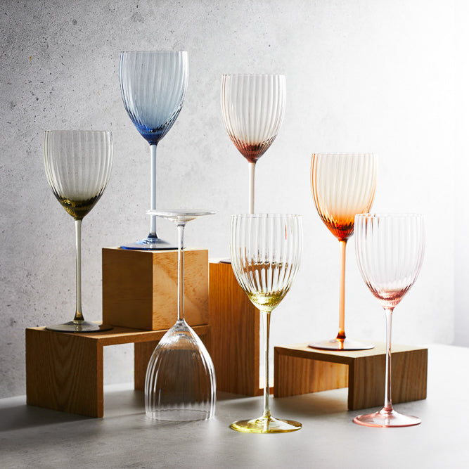 A collection of various colors of Quinn crystal white wine glasses from Caskata.