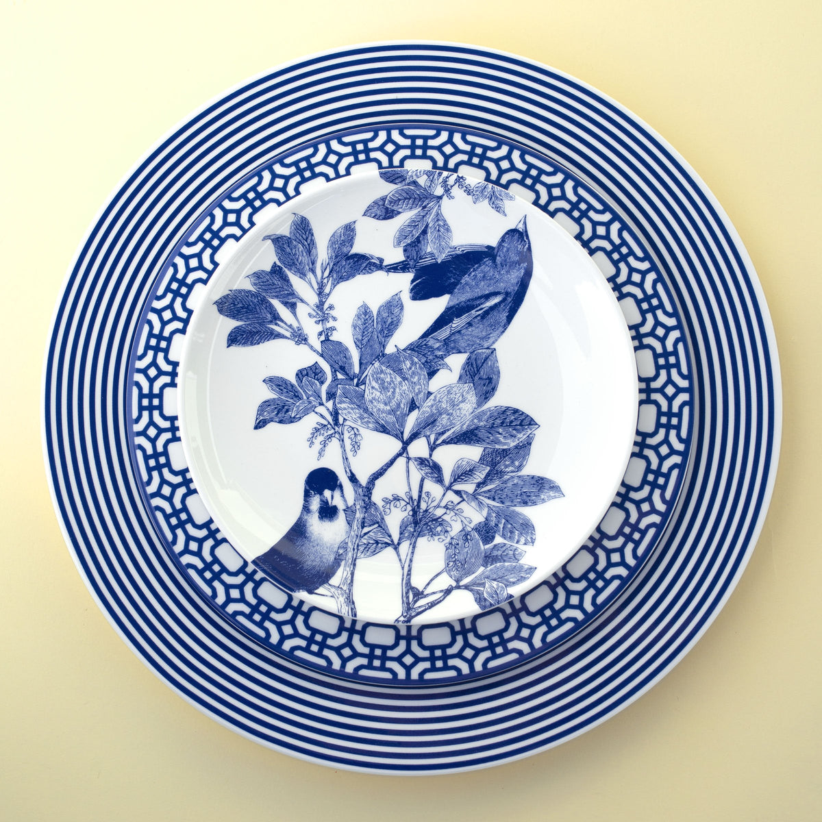 A blue and white Newport 4-Piece Place Setting with birds from the Caskata Artisanal Home dinnerware collection.