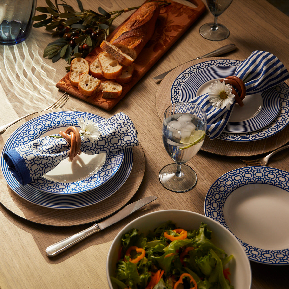 A blue and white plate with a Caskata Newport Garden Gate Dinner Napkins in Blue Set/4 salad on it.
