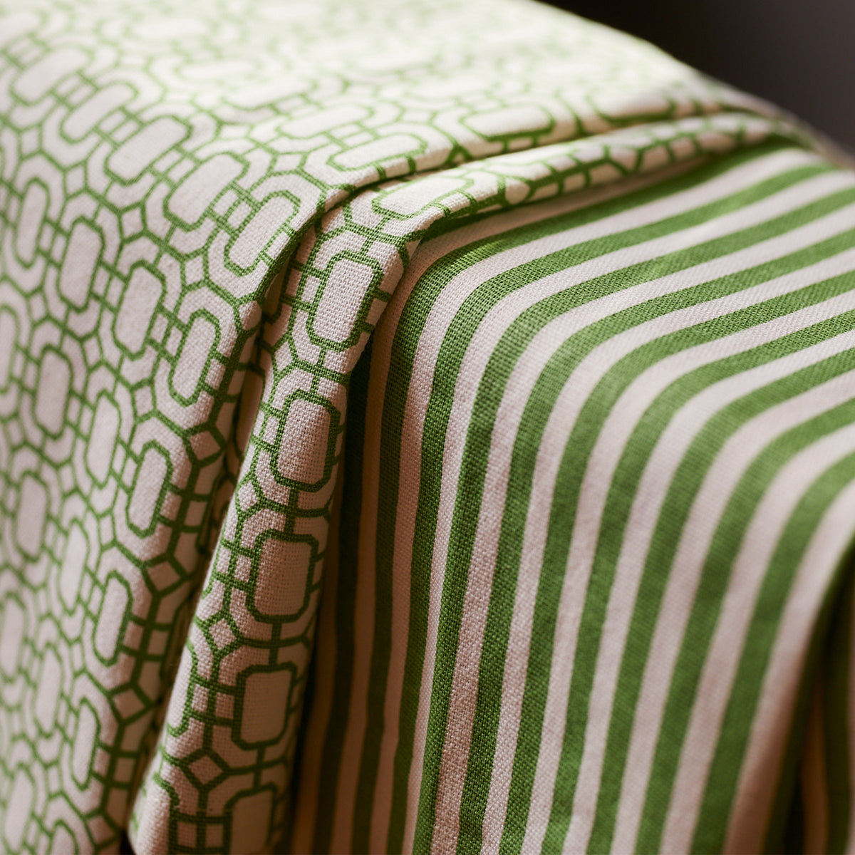 Close-up of two green and white patterned fabrics draped over a surface. One fabric features geometric shapes, while the other has vertical stripes—Caskata Newport Garden Gate &amp; Pinstripe Verde Kitchen Towels, Mixed Set of 2 that become your ideal kitchen companions.