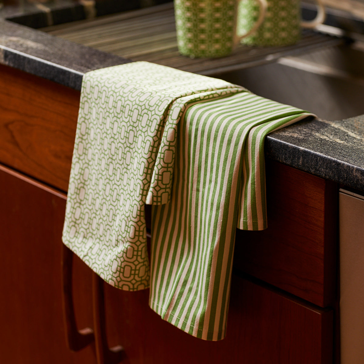 Caskata&#39;s Newport Garden Gate &amp; Pinstripe Green Kitchen Towels Mixed Set/2 in spring green and white, are hanging on a kitchen counter.