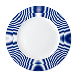 A white Newport Stripe Rimmed Dinner Plate by Caskata Artisanal Home with concentric blue circles around the edge, perfect for contemporary dinnerware collections.