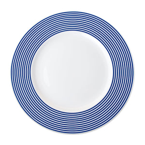 A white Newport Stripe Rimmed Dinner Plate by Caskata Artisanal Home with concentric blue circles around the edge, perfect for contemporary dinnerware collections.
