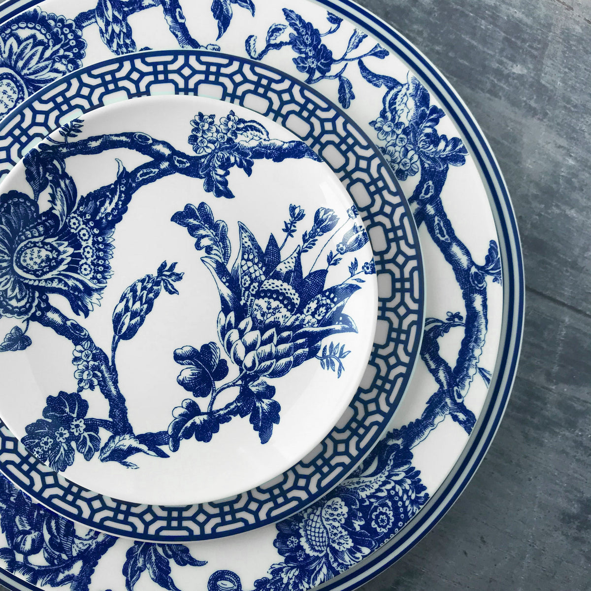 A Newport Blue Charger Plate by Caskata Artisanal Home, a blue and white porcelain dinnerware with a floral pattern.