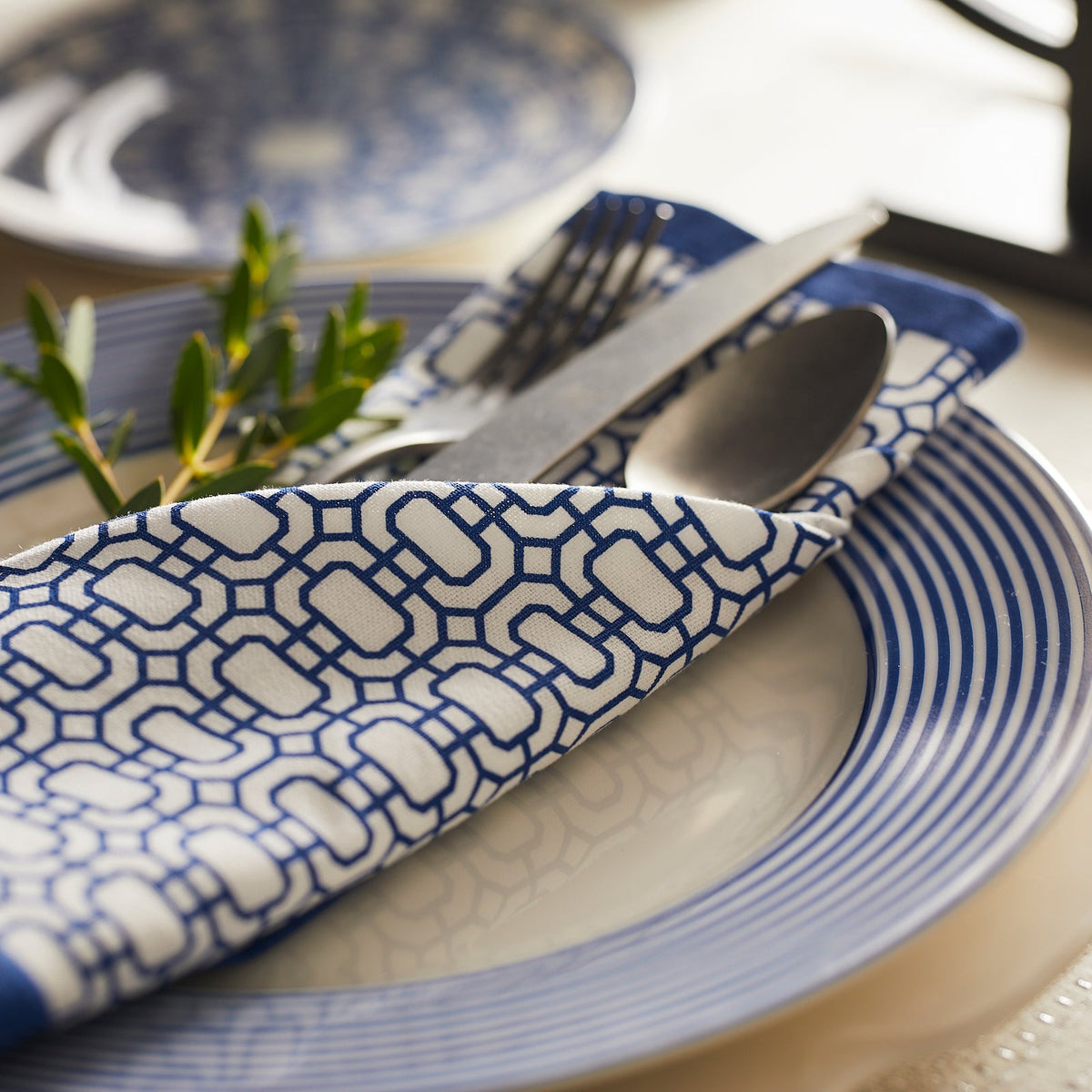 A Caskata Newport Garden Gate dinner napkin, featuring a signature blue and white design.