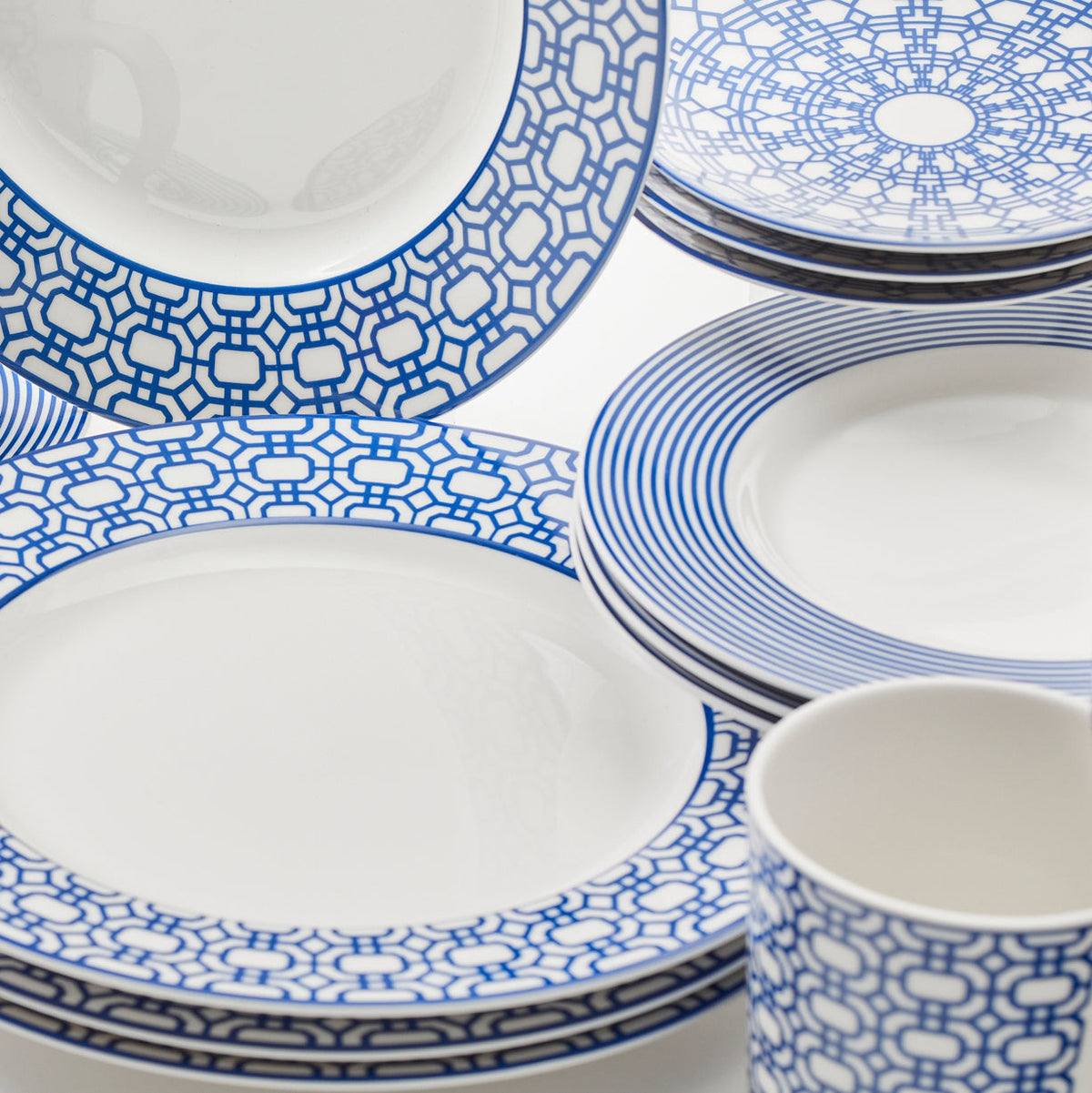 A Caskata Newport Garden Gate Table for 4, perfect for any dinnerware collection. The set of blue and white plates and cups is not only stylish but also practical, as it is microwave and dishwasher safe.
