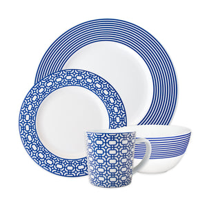 The Caskata Artisanal Home Newport 4-Piece Place Setting features a plate, salad plate, bowl, and mug with blue geometric patterns and stripes on white porcelain; dishwasher safe for easy cleaning.