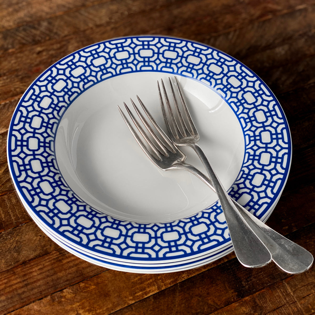 A blue and white Caskata Artisanal Home Newport Garden Gate Rimmed Soup Bowl with a fork.
