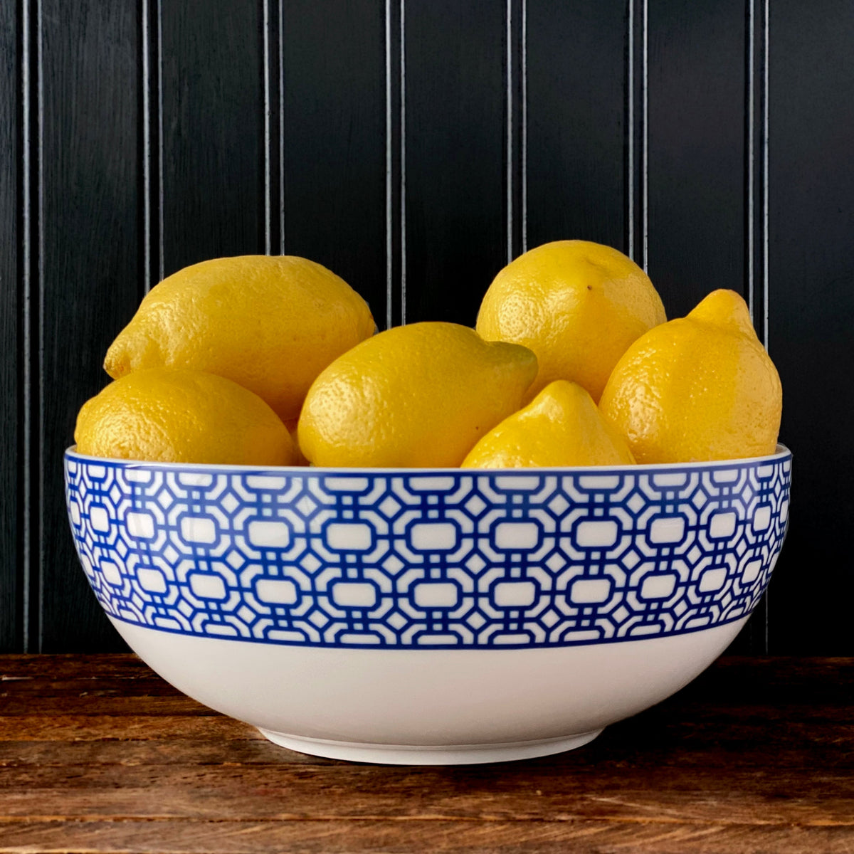 A Newport Garden Gate Vegetable Serving Bowl by Caskata Artisanal Home filled with lemons.