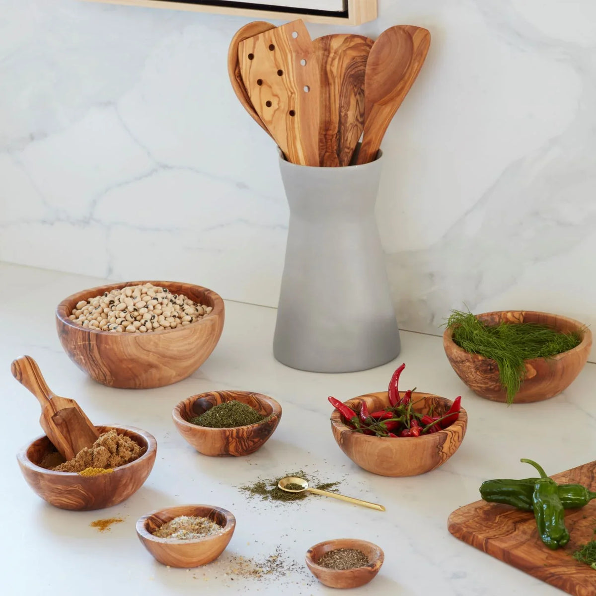 A set of Be Home Olive Wood Nesting Bowls, Set of 6 and spoons on a counter.