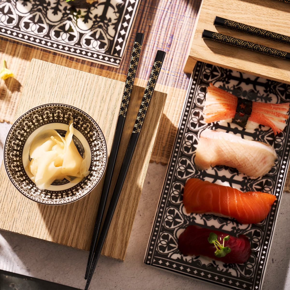 Japanese food adorned with gold patterns, served on a lacquered wood table with Osaka Chopsticks from Miya, Inc.
