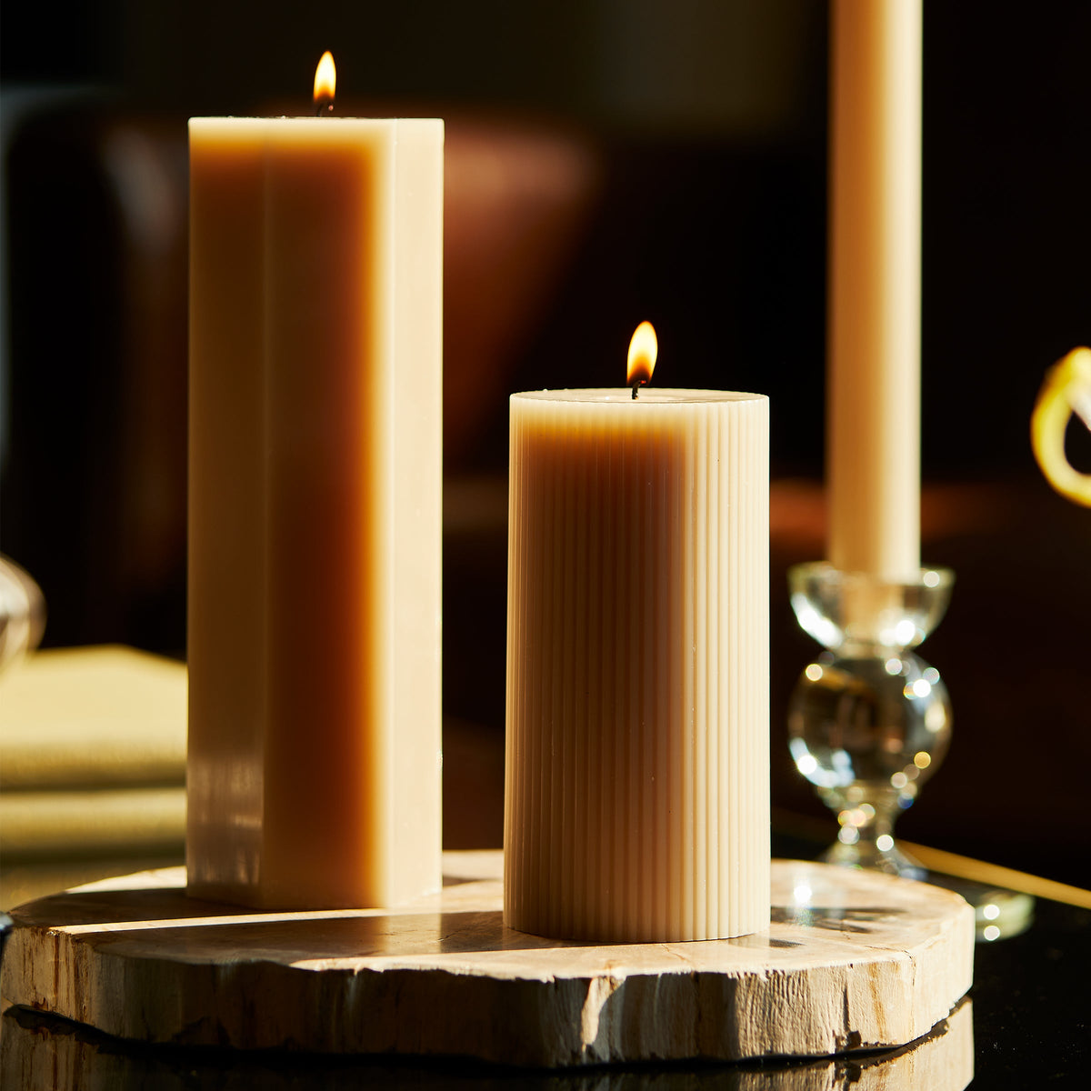 Ribbed Pillar Candle in Parchment White 6 inch from Caskata, surrounded by a larger pillar and candlestick in same color.