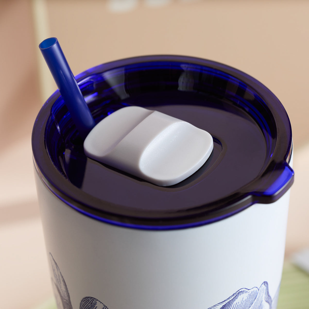 Presenting the Caskata Peony Stainless Steel Insulated Tumbler: a chic blue and white design with vacuum insulation, featuring a blue straw and a practical white flip-top lid.