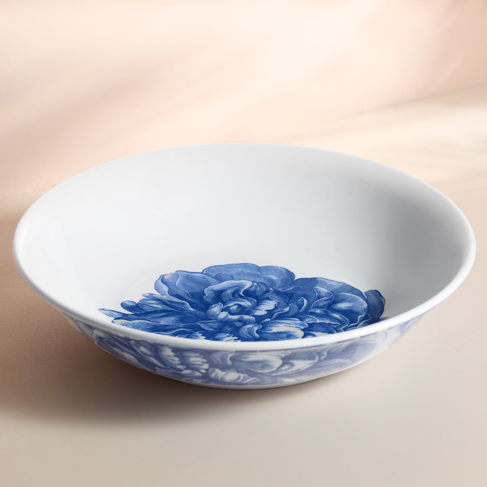 The Peony Melamine Serving Bowl by Caskata showcases a sophisticated blue peony design both inside and out, set against a light background, radiating durable elegance.