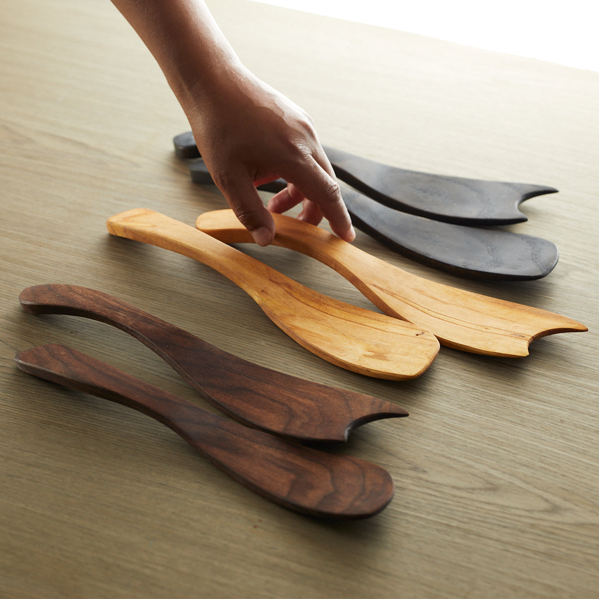 Four Peterman&#39;s Ebonized Oak Handcrafted Salad Tossers, placed side by side on a table.