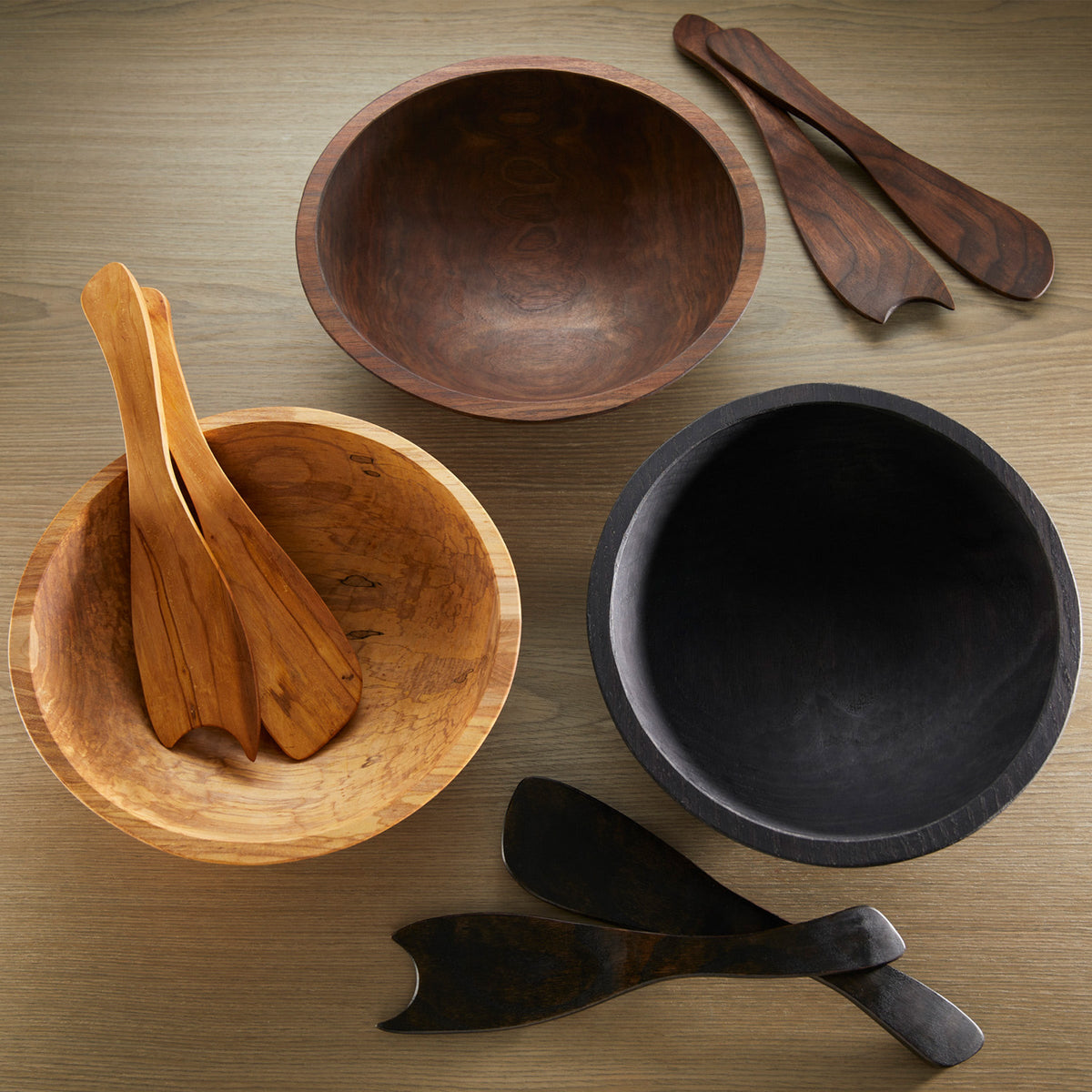 Four Peterman&#39;s handmade wooden Black Walnut 13&quot; Handcrafted Serving Bowls and utensils, crafted from black walnut, on a table.
