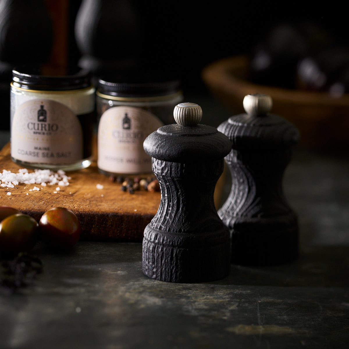 Bistro 4&quot; Black Salt &amp; Pepper Mills by Peugeot on a wooden cutting board.