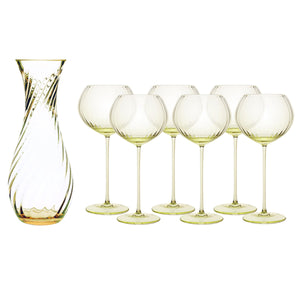 The Quinn Citrine Red Wine Lover Set by Caskata features a clear glass carafe with a swirl pattern and six matching crystal red wine glasses, all with a subtle yellow-green tint and exquisite Czech craftsmanship.