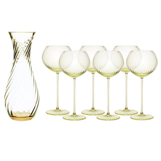 The Quinn Citrine Red Wine Lover Set by Caskata features a clear glass carafe with a swirl pattern and six matching crystal red wine glasses, all with a subtle yellow-green tint and exquisite Czech craftsmanship.