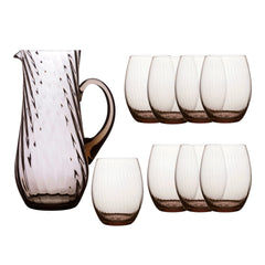 The Quinn Mocha Sangria Set by Caskata features a clear, mouth-blown crystal pitcher with a handle and six matching textured stemless glasses, all crafted in the Czech Republic.