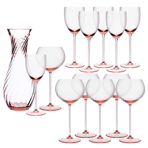 The Quinn Rose Wine Lovers Set by Caskata includes nine pink-tinted crystal wine glasses, two wide-bowl glasses, and a matching carafe, all featuring a textured swirl pattern.