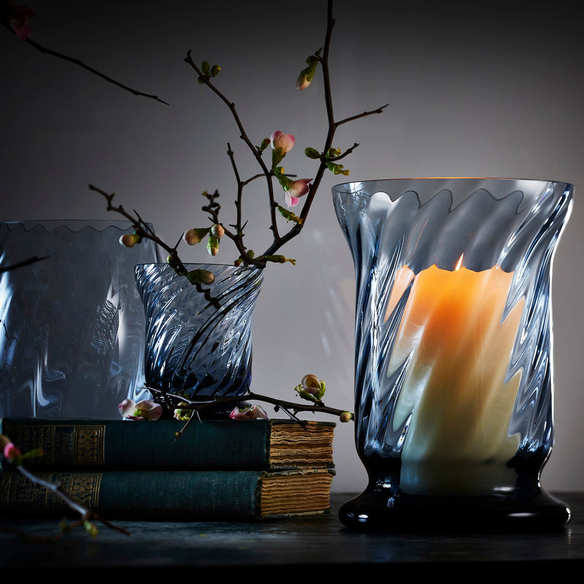 Caskata ocean blue candle holders in three different styles: Votive, Boothbay and Eliot Hurricanes. Photo features antique books and cherry blossoms.