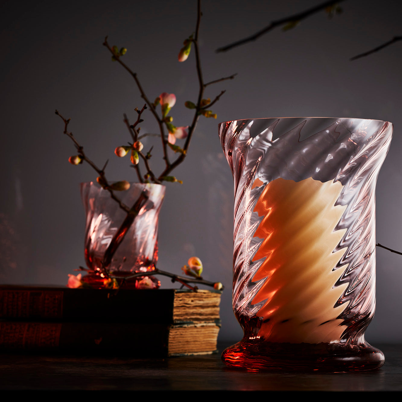 The Quinn Rose Candlelight Bundle by Caskata features three pink glass tumblers with a spiral pattern, crafted from mouth-blown Czech Republic lead-free crystal, including two smaller and one larger piece, elegantly displayed against a white background.
