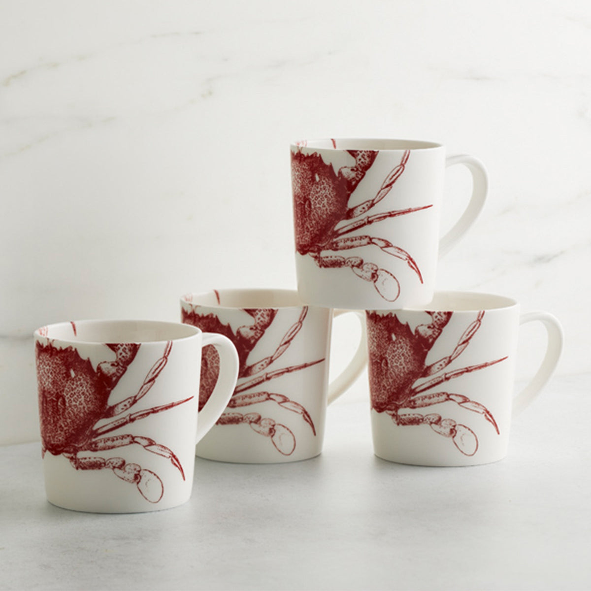 Four Caskata Artisanal Home Crab Red Mugs with large red crabs on them, perfect for coastal whimsy enthusiasts. These mugs are dishwasher and microwave safe.