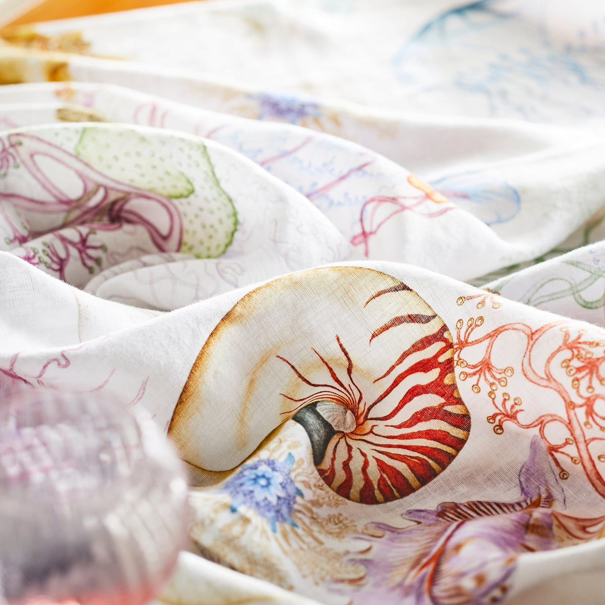 A set of colorful Reef Hemp Tablecloth towels with playful nautilus shells on them, from the brand TTT.