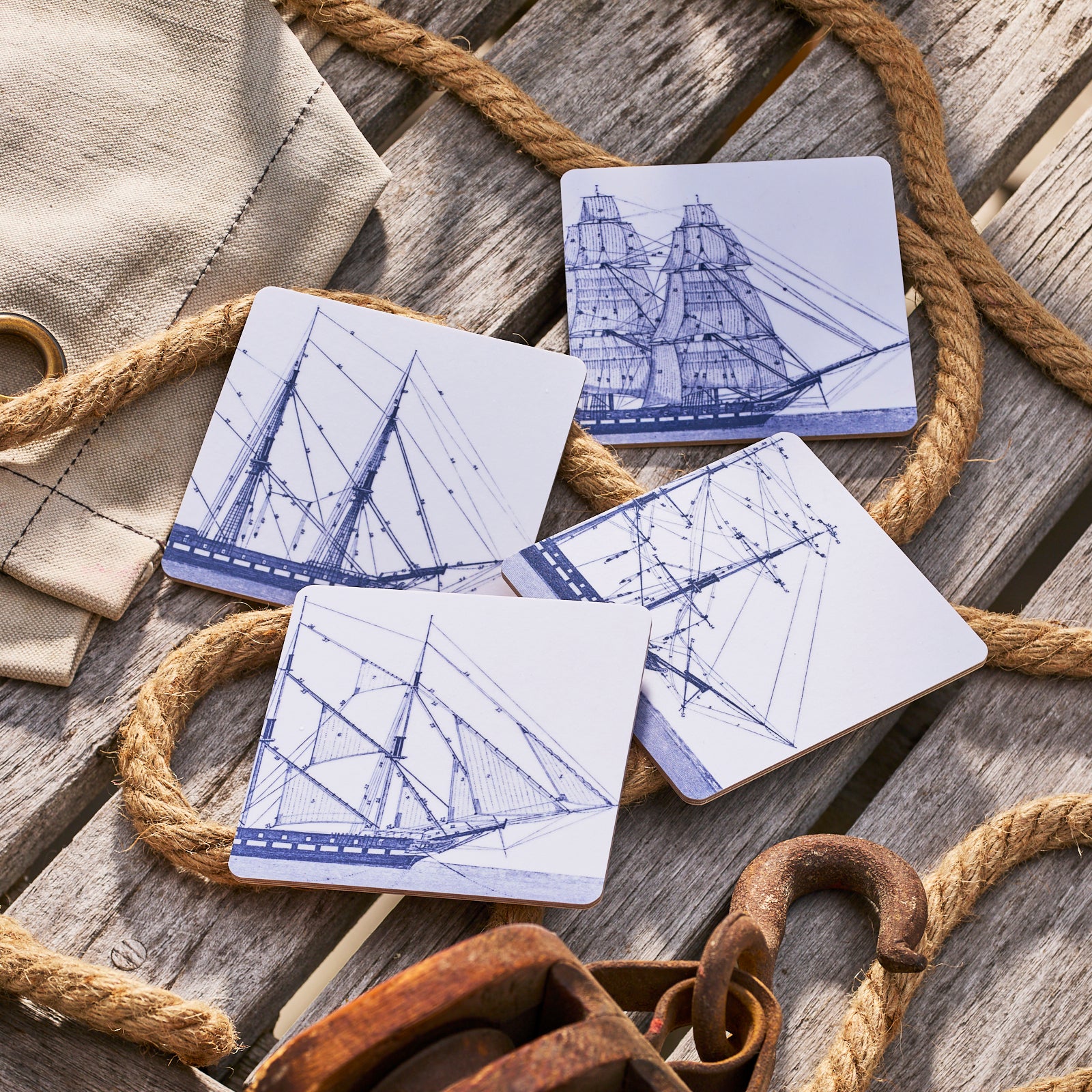 The Caskata Rigging Birchwood Square Coasters, Set of 4, feature white squares with detailed blue sailing ship drawings—each unique—designed to pair perfectly with your FSC-Certified Birchwood trays.