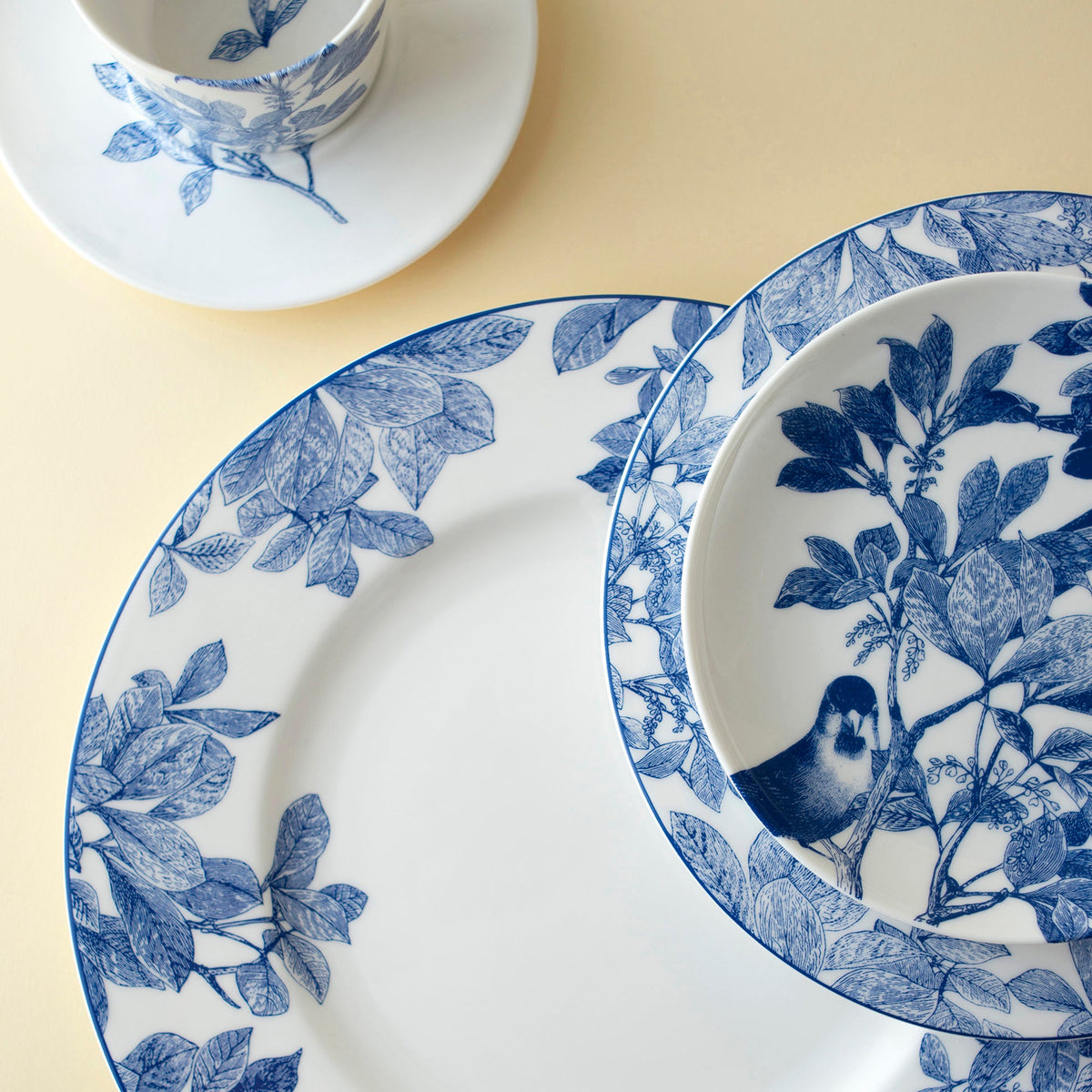 The blue and white Arbor pattern by Caskata includes porcelain dinner, salad, and canape plates and cup and saucer.