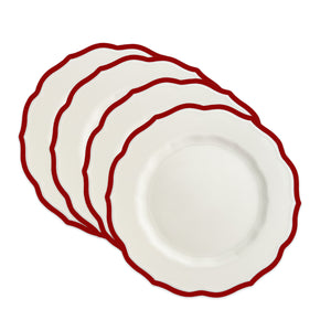 Four Caskata Stella Scalloped Crimson Salad Plates are stacked in a staggered arrangement, showcasing their white finish, red border, and scalloped edges.