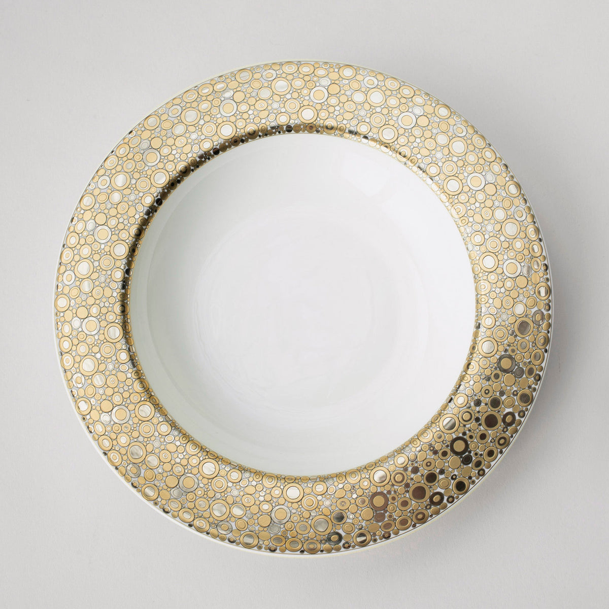 An Ellington Shimmer Gold &amp; Platinum Rimmed Soup Bowl by Caskata Artisanal Home on a white surface.