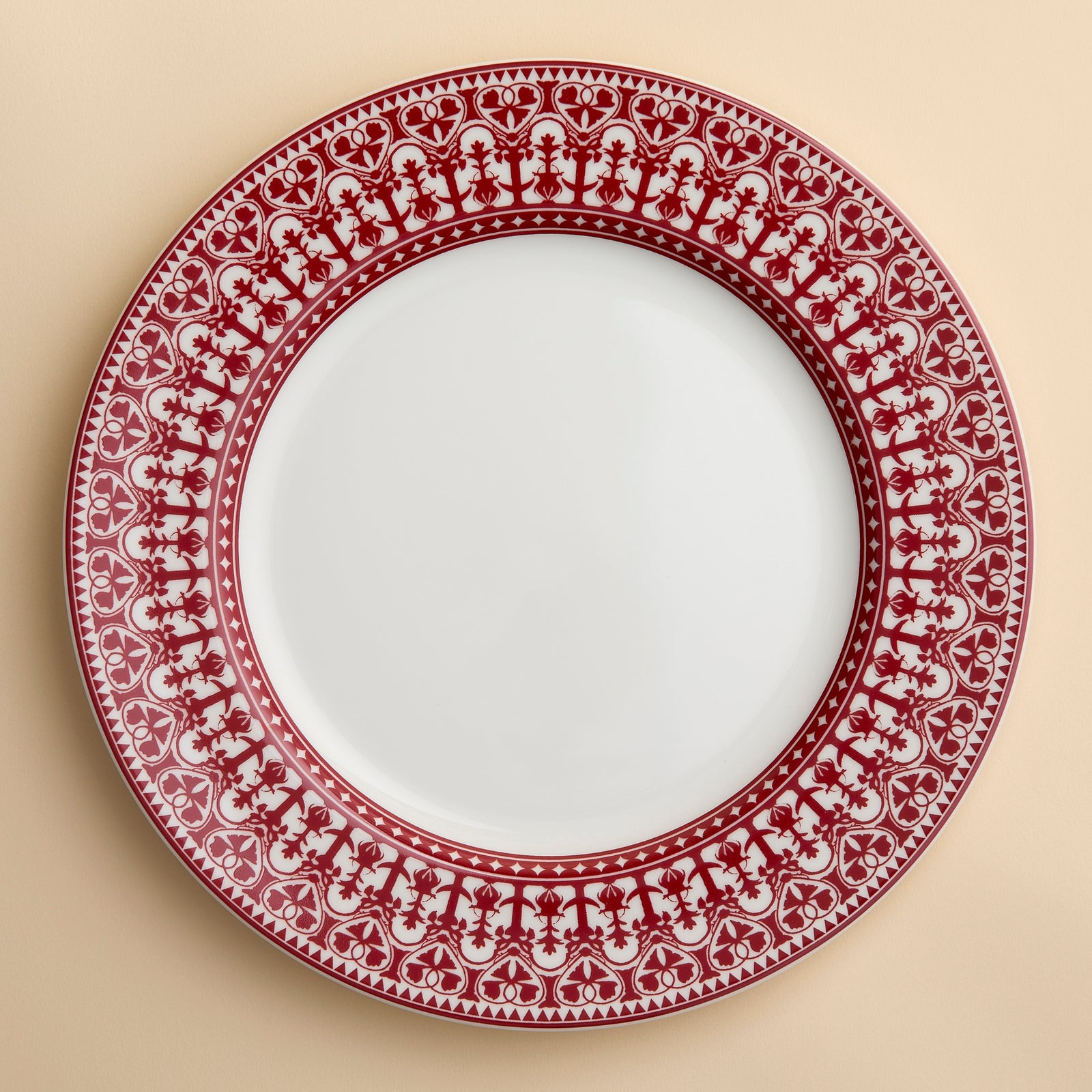 RIch crimson red in the Casablanca pattern circles this rimmed porcelain dinner plate from Caskata