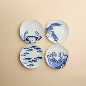 A set of four dishwasher-safe porcelain Coastal Icons Small Plates, Mixed Set of 4, each featuring a blue marine life illustration of a crab, lobster, school of fish, or octopus.