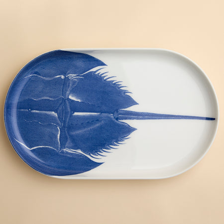 A highly detailed engraving of a horseshoe Crab in brilliant blue adorns this large oval platter from Caskata in premium porcelain, 