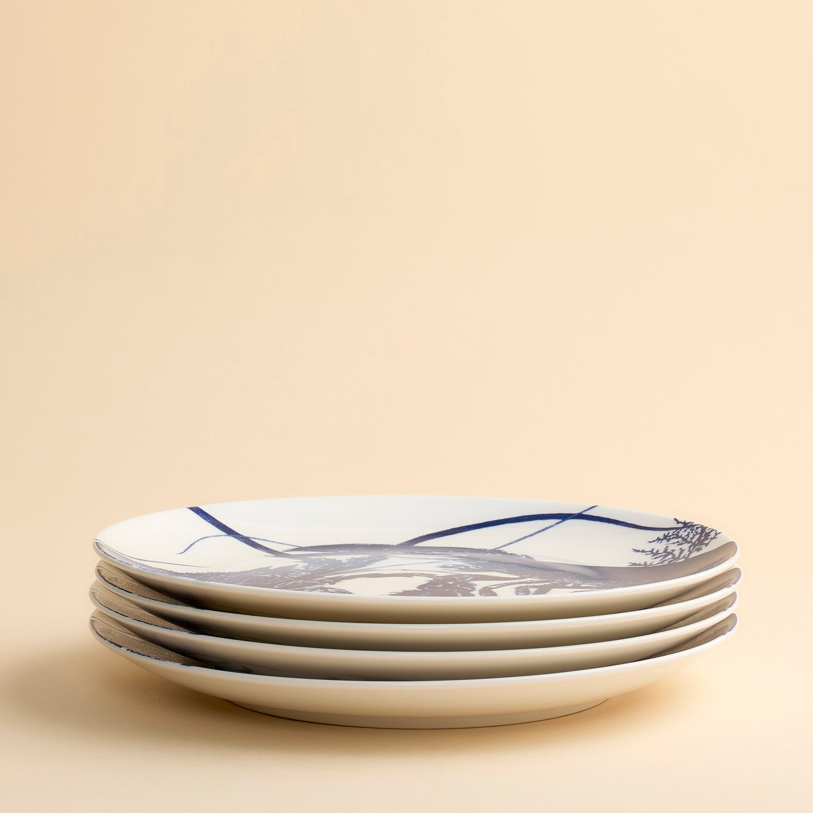 Blue lobsters, one from the East, one from the West, lock in a graphic embrace across the face of this coupe porcelain dinner plate from Caskata.