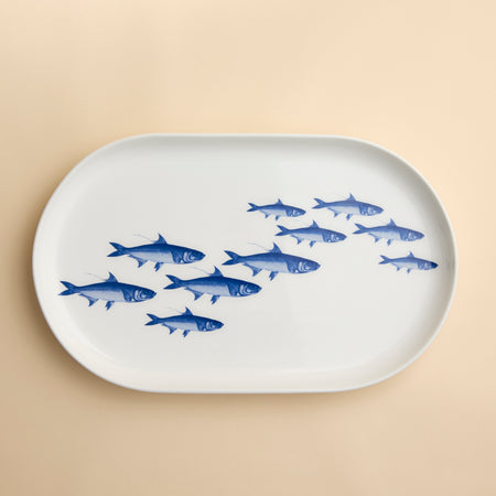 A bright blue School of Fish swims across the face of this contemporary styled coupe serving platter in high-fired porcelain from Caskata.