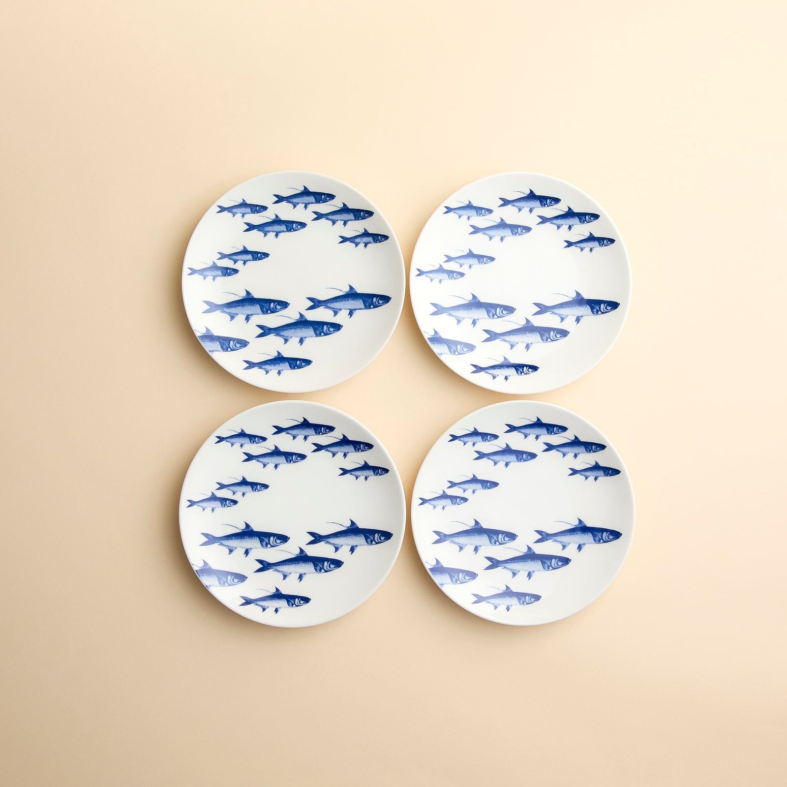 A brilliant blue School of Fish swim across this set of 4 mall plate appetizer dishes in high-fired porcelain from Caskata.