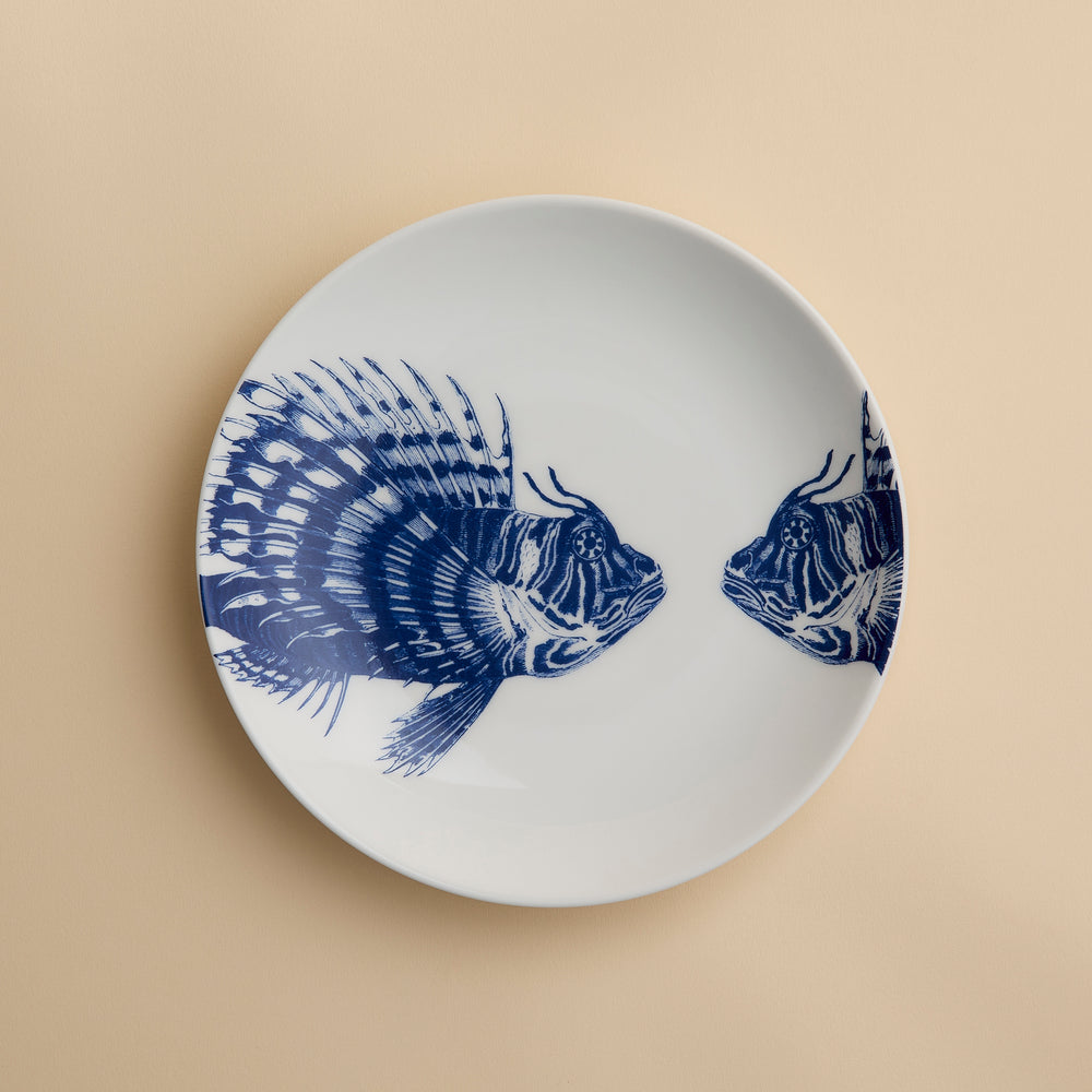 Add a playful coastal vibe to your dining table with the Caskata Spiky Fish Coupe Salad Plate—this white porcelain plate features two blue fish illustrations facing each other and is perfect for enhancing your coastal dinnerware collection.