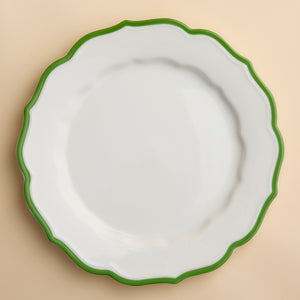 The Stella Scalloped Verde Dinner Plate by Caskata features a white design with a green border, embodying the timeless charm of vintage dinnerware in high-fired porcelain.