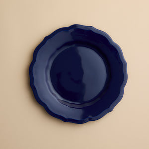 A solid dark blue Caskata Stella Scalloped Solid Blue Salad Plate with a scalloped edge.