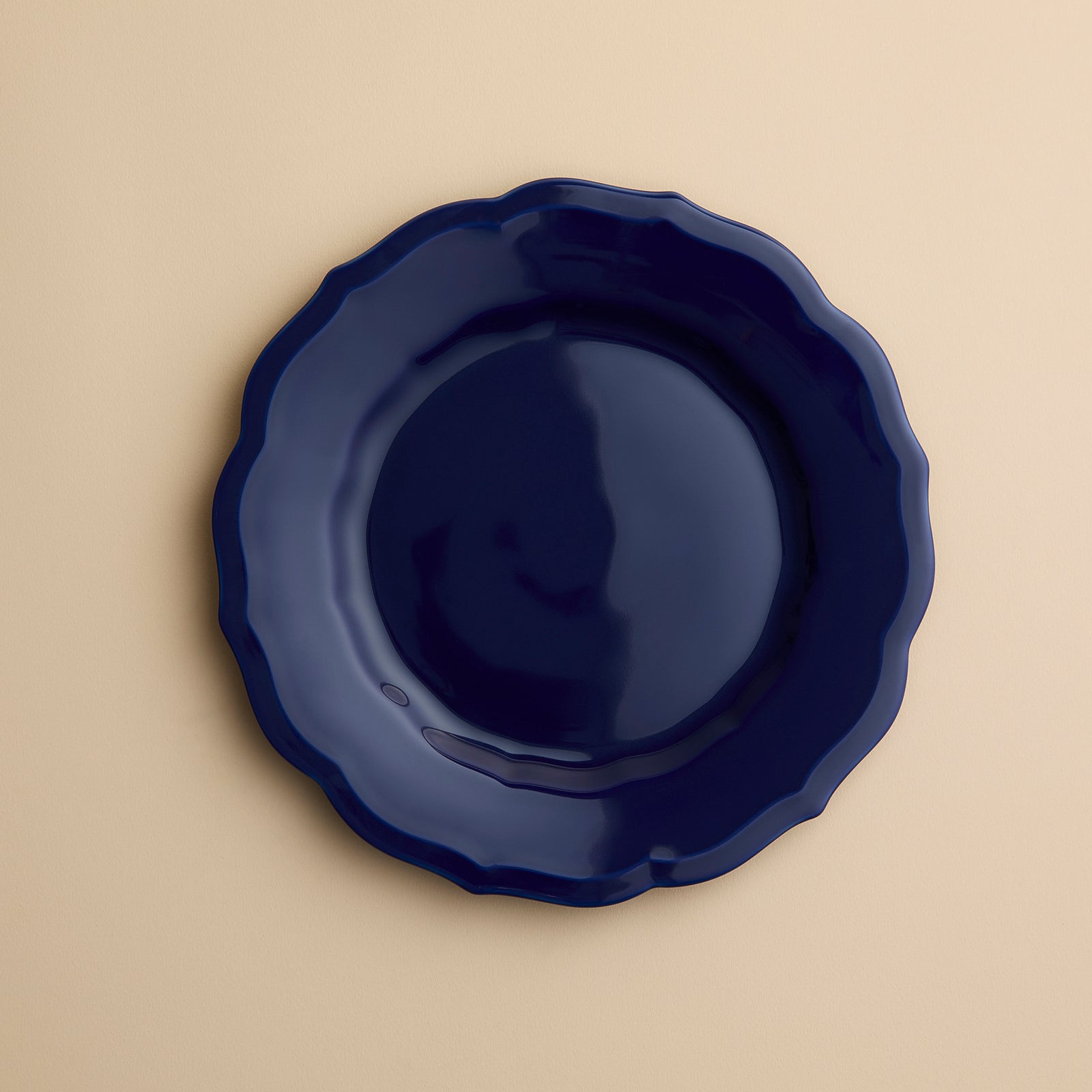 A solid dark blue Caskata Stella Scalloped Solid Blue Salad Plate with a scalloped edge.