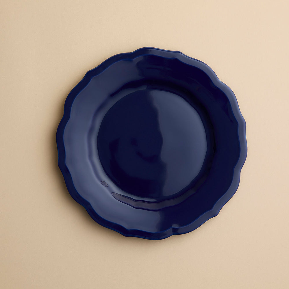 A solid dark blue Caskata Stella Scalloped Solid Blue Salad Plate with a scalloped edge.