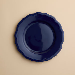 A solid dark blue Caskata Stella Scalloped Solid Blue Salad Plate with a scalloped edge.