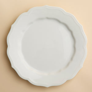 The Stella Scalloped White Dinner Plate by Caskata is a round porcelain dish featuring a scalloped edge, offering a vintage vibe that seamlessly complements any neutral palette or dinnerware design.