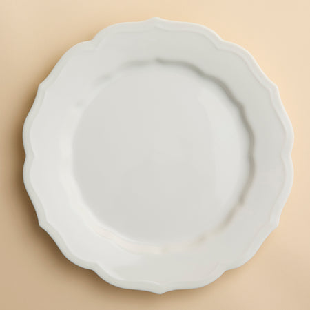 The Stella Scalloped White Dinner Plate by Caskata is a round porcelain dish featuring a scalloped edge, offering a vintage vibe that seamlessly complements any neutral palette or dinnerware design.