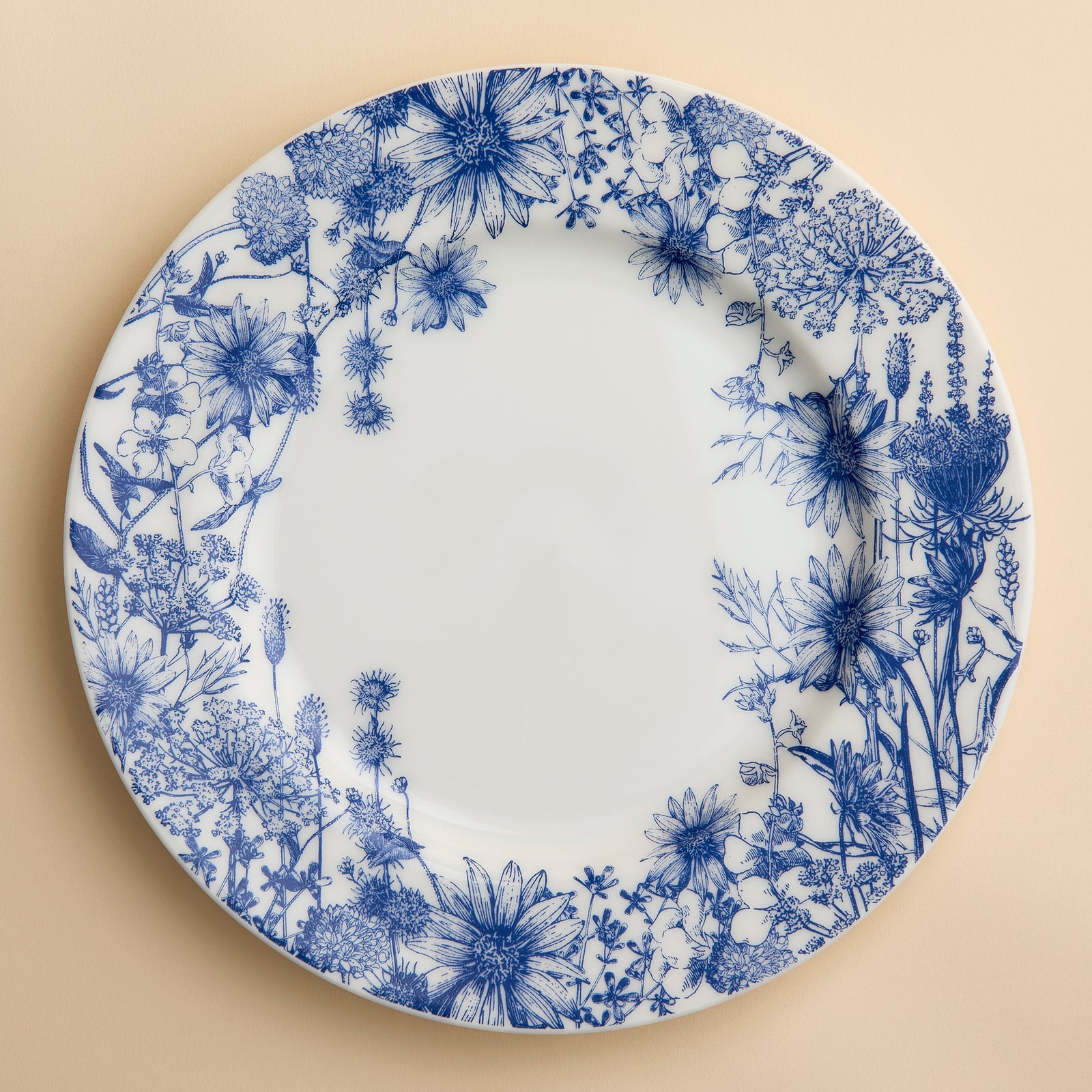 Summer Blues Floral porcelain Dinner plate in bue and white with wildflowers around the rim on a creamy beige background.