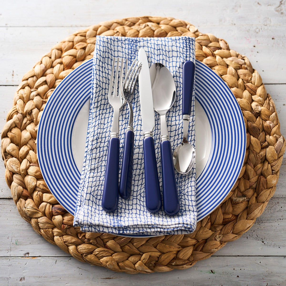 A Newport Racing Stripe Rimmed Dinner Plate in blue and white by Caskata Artisanal Home.