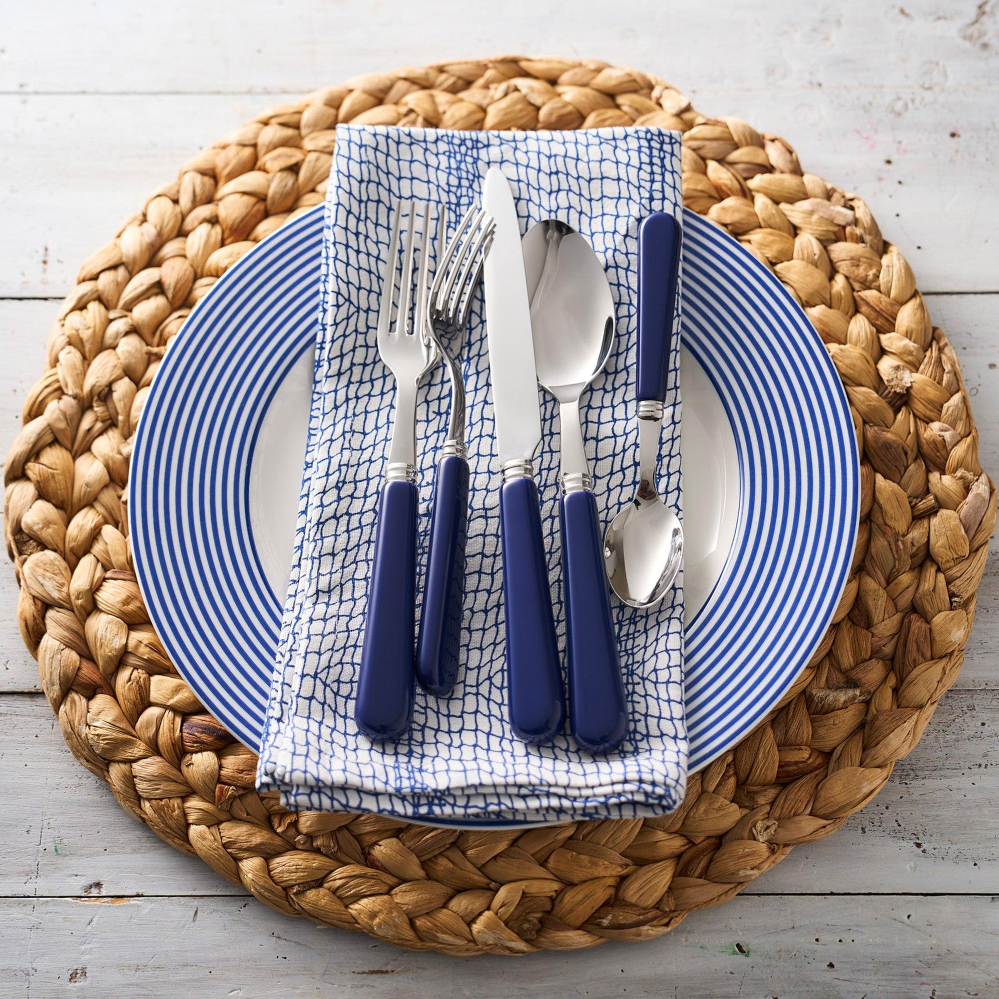 A white Newport Stripe Rimmed Dinner Plate by Caskata Artisanal Home with concentric blue circles around the edge, perfect for contemporary dinnerware collections.